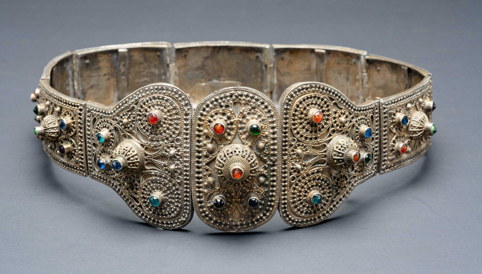 A massive gilt silver wedding belt- Kafkaz islamic: The belt is comprised of large wrought silver plaques, Fine filigree and granulated silver decorates the plaques, Set with colorful cabochons The belt closes by linking the two parts on two hooks. Eac