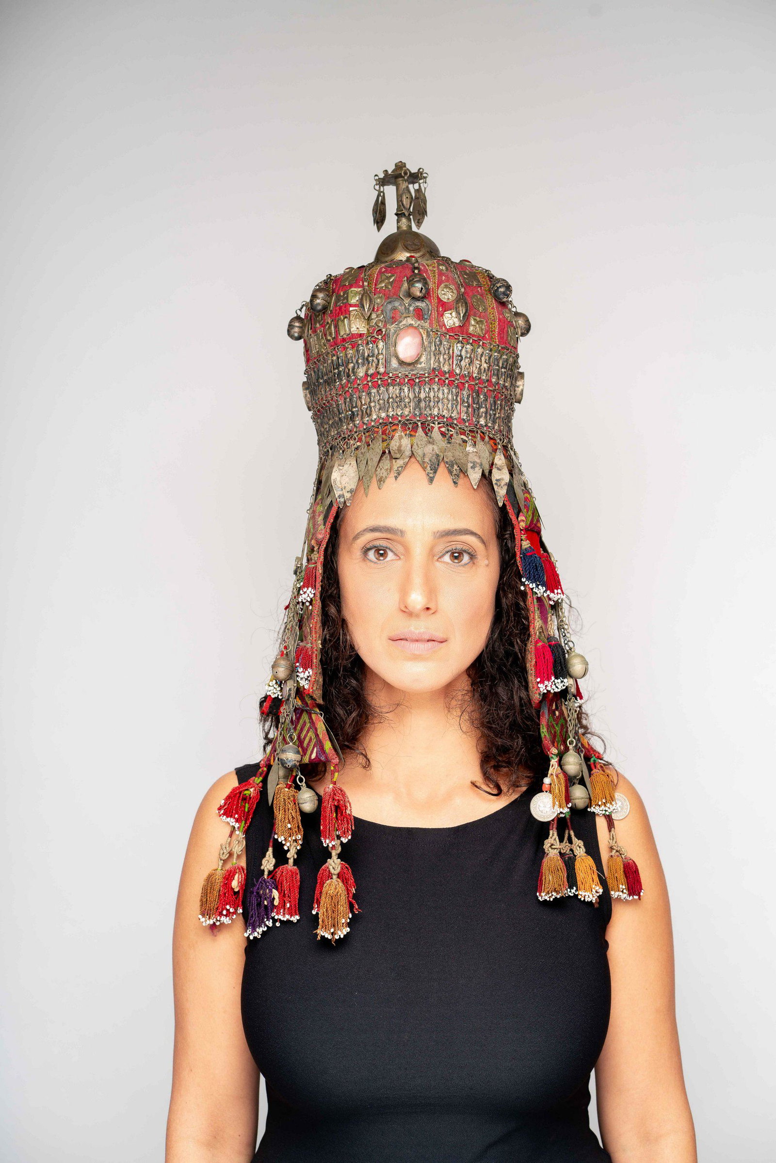 A tribal head piece with silver ornamentation turkmen: The headpiece has hanging embroidered triangle ornamentation. many cut and punched silver elements adorn the piece. Large carnelian stones set throughout. Silver organic elements hang from the sides. 