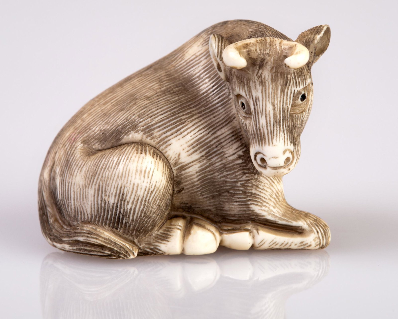 fine antler / bone netsuke: An old netsuke, depicting reclining bull. Signed. H 3 cm , W 2.5 cm, L 3.8 cm