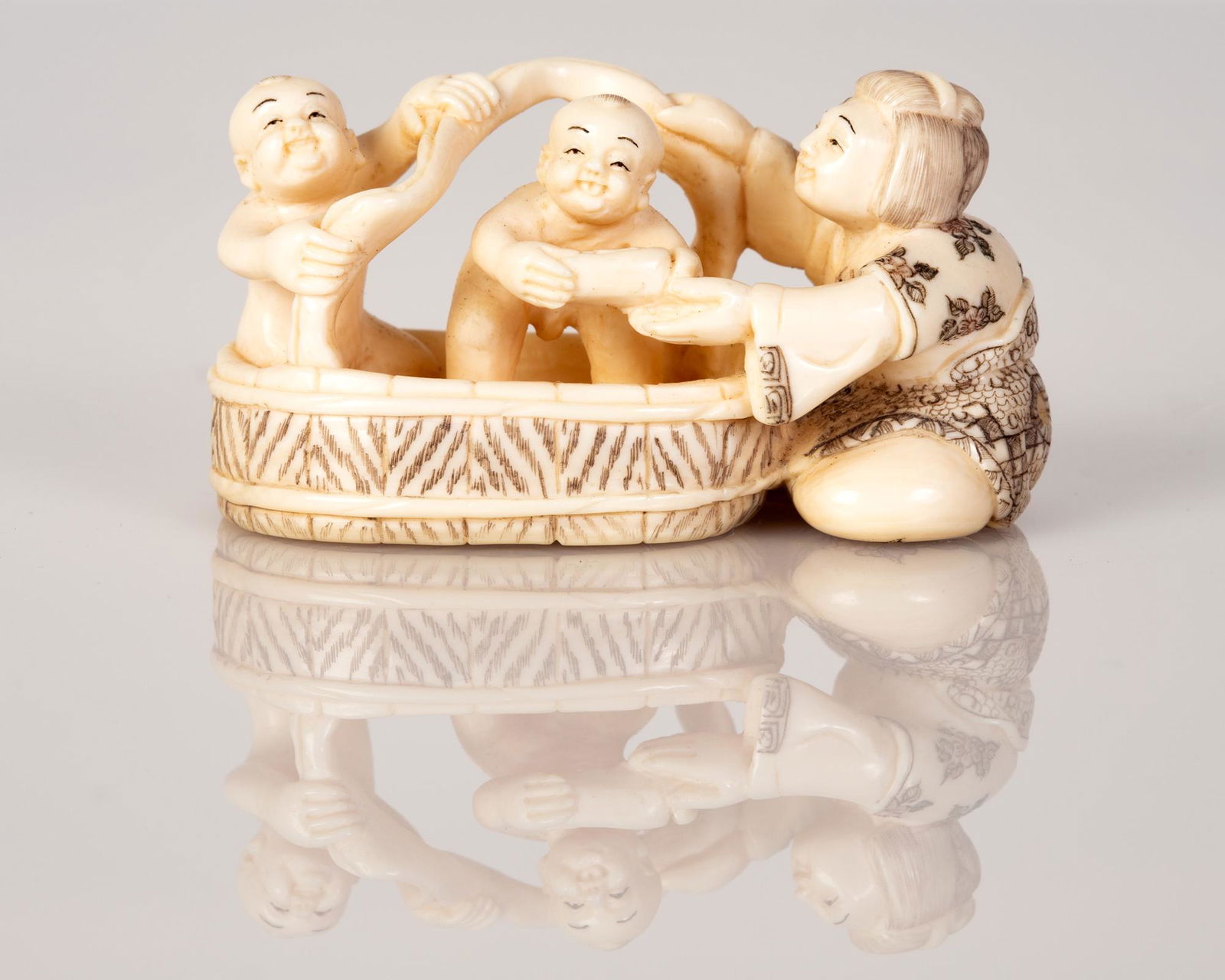 Old Bone Netsuke Scene Mother Bathing Her Children in: Old Bone Netsuke with a scene of a Mother Bathing Her Children in a Water Tub. Item illustrated by hand and signed. Dimensions: 4X2X2 cm.