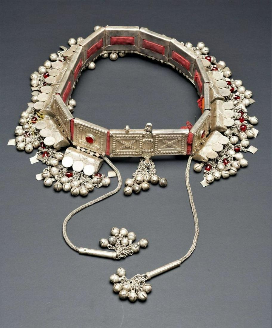 An impressive and rare silver belt of Jewish bride -: The large belt is comprised of 13 silver rectangular plaques, decorated with granulation and woven into a red textile. Some of the plaques are set with faceted red glass. A woven silver rope decorated