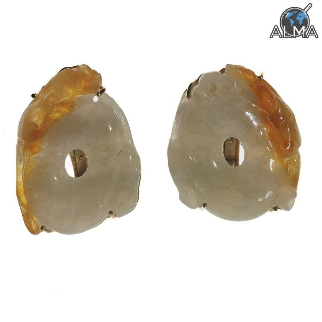 Pair of Chinese 14K Gold, Jadeite Jade Earrings: Yellow gold earrings with posts and hinged clip backs, containing two carved natural color white (mutton fat) and yellow Jadeite Jade disks measuring approximately 30 x 26 mm. Weight: 28.7 grams Stamp