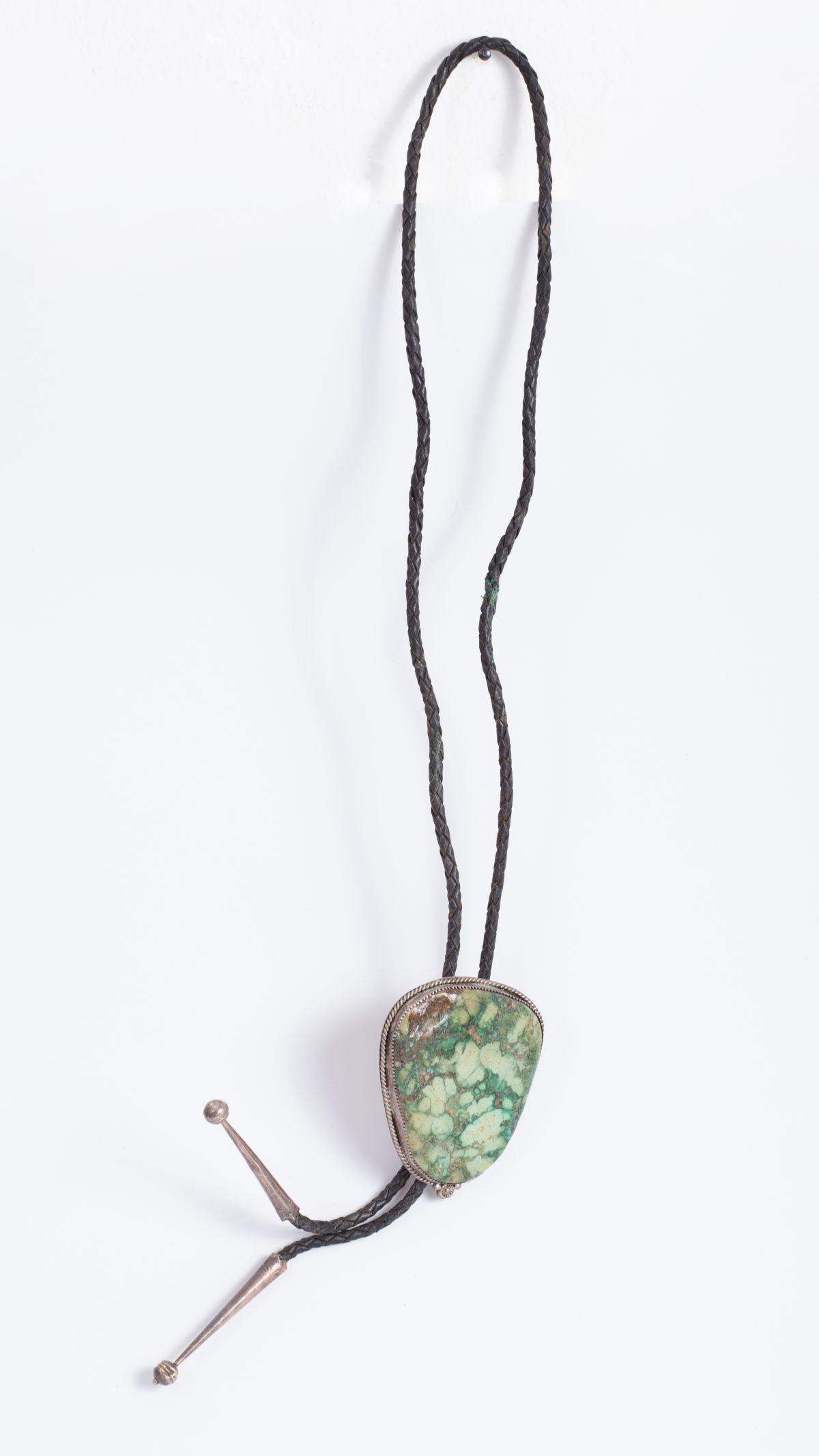 Oversized "boloe tie" Native American necklace- early 1900's: the necklace is comprised of a leather band with an oversized turquoise set in silver as the center piece. two silver cone shaped finials are at the end of the leather band. A mechanism allows one to 