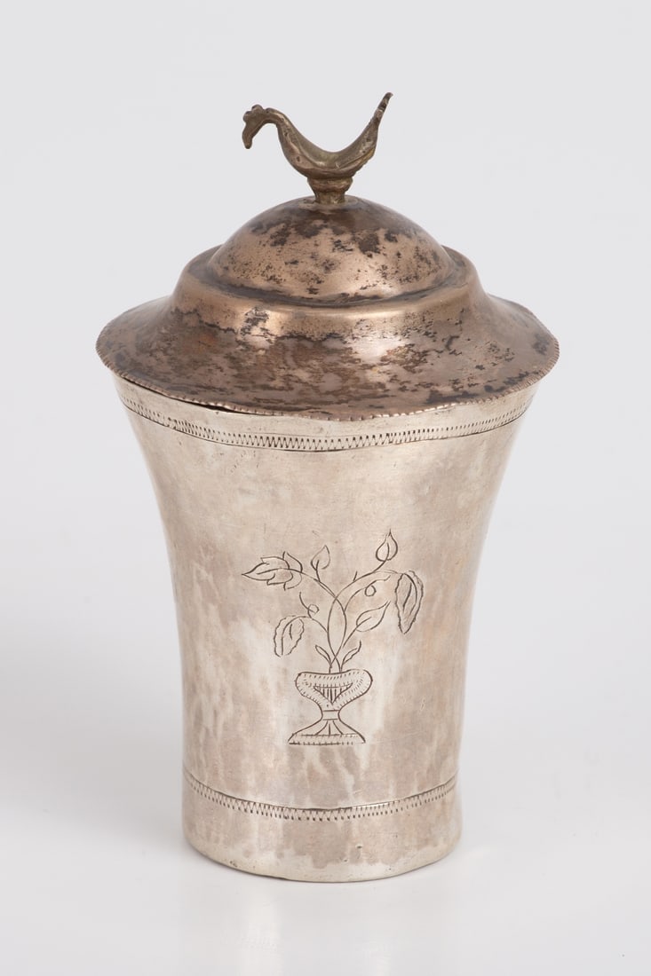 Silver Kiddush Cup with Cover, Iraq. 19th-20th C: The cup is adorned with organic and geometric engravings, accompanied by a matching cover featuring a bird figurine. Height (with the cover) - 14 cm. Diameter - 8 cm. Weight - 201 grams.