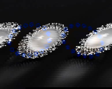 14K white gold earrings set with moonstone and blue gems: A pair of earrings made of 14 carat white gold (signed) set with moonstone surrounded by a halo of blue gems. clip on Dimensions: about 1.5x2 cm Total weight: 10 grams