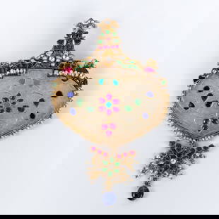 pendant in a Mogul style, with diamonds and gemstones: At the center of the pendant, there is a white jade plaque set within a golden silver frame adorned with tiny pearls. The jade plaque is embellished with rubies, turquoise, emeralds, and diamonds. 