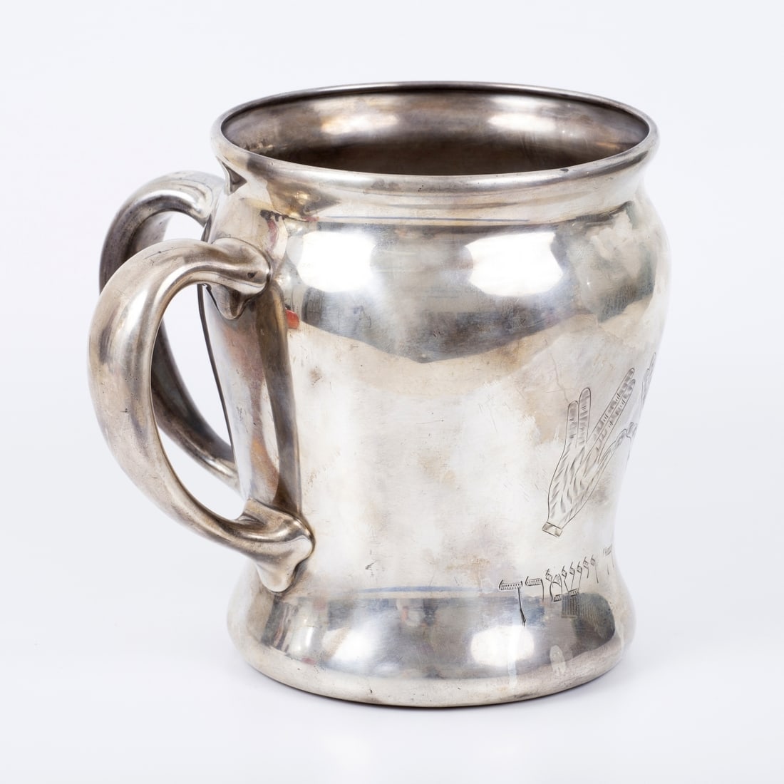 A large silver handwashing vessel for the priests in the synagogue,: The center of the vessel is adorned with exquisite engravings depicting the hands of the priest raising palms to bless, and beneath is inscribed the beginning of the Priestly Blessing: "May the L