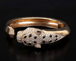 "Panthère de Cartier" - A luxurious gold bracelet adorned with diamonds, emeralds, and onyx stones.