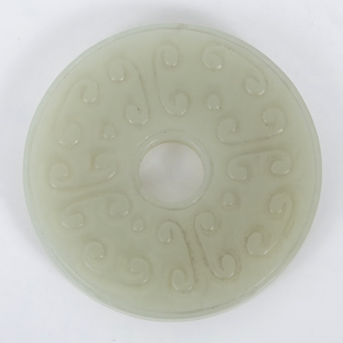 Carved jade disc, China - Qing Dynasty (1644-1911): One side features a scene with a mythical sea monster, while the other side is decorated with an organic pattern. Diameter: 5.5 cm. Small and minor chip on the edge.
