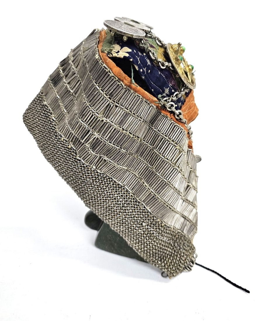 Ottoman? cap with silver knitting and coins: A head covering made of knitted silver sheets, with rows of silver tubes on a fabric lining featuring a dark-colored embroidered medallion. The piece is accompanied by silver coins from the Russian Em
