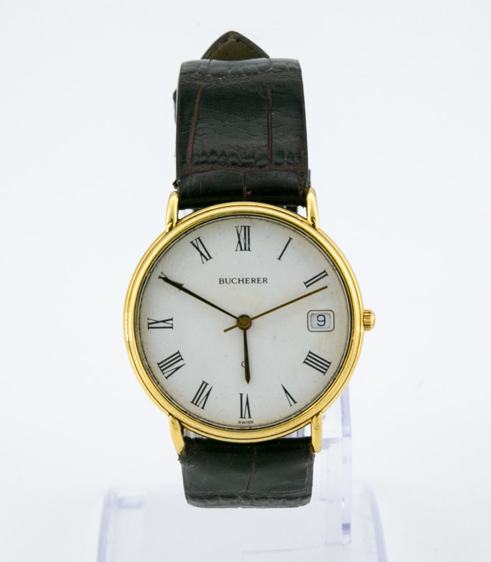 A Vintage Bucherer 18K Gold Unisex Wristwatch: A Vintage Bucherer 18K Gold Unisex Wristwatch Mechanism: Quartz Complication: Date Case: 18K Gold (marked) Dial: White with Roman numerals Band: Brown leather strap. Not original Diameter: 3