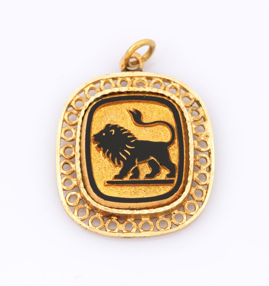 A 14K Yellow Gold and Black Enamel Lion Pendant: A 14K Yellow Gold and Black Enamel Lion Pendant Designed as a rounded rectangle with a pierced bezel, centering a carved lion in black enamel on a brushed gold ground. The reverse set with a black sto
