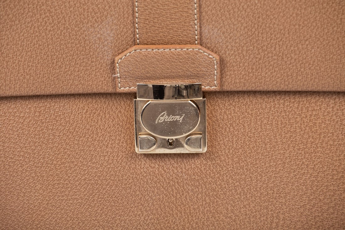 A Brioni Leather Document Case, Italy: A Brioni Leather Document Case, Italy A fine leather document case by Brioni, in light tone, with matching fabric strap fitted with gilt metal elements. Very good overall condition. Height: 36 c