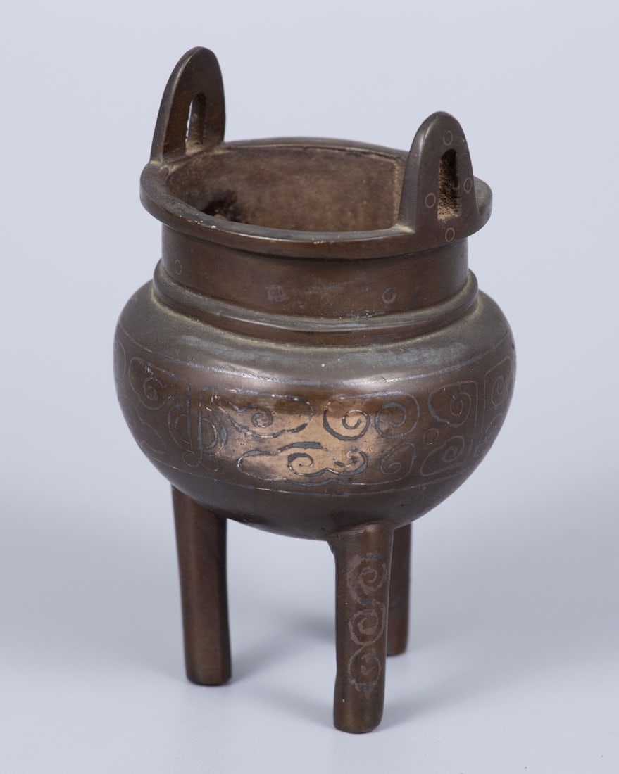 A Bronze and Silver Inlay Censer, China, Qing Dynasty (1644-1912): A Bronze and Silver Inlay Censer, China, Qing Dynasty (1644-1912) In tripod form, inlaid with silver wire. Decorated with traditional geometric engravings.Height: 12 cmCondition: For a full condition
