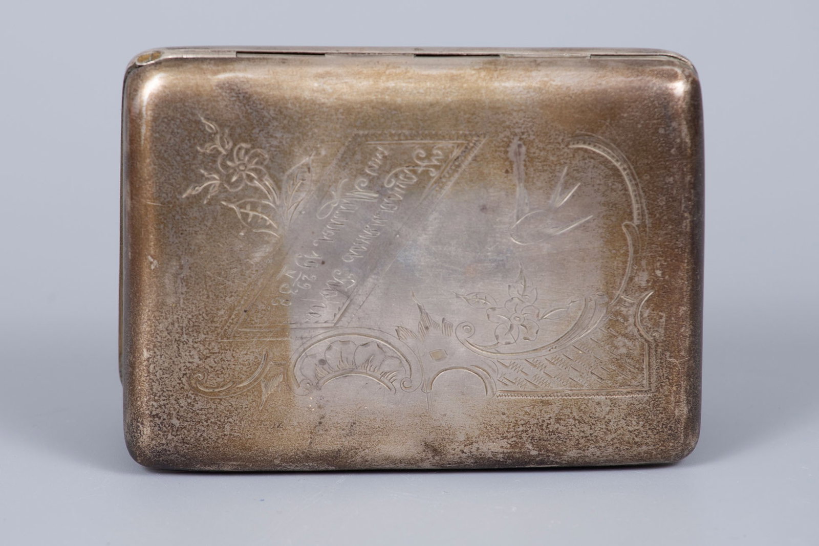 A Parcel Gilt Silver Cigarette Case, Russia, Early 20th Century: A Parcel Gilt Silver Cigarette Case, Russia, Early 20th Century Decorated with ornamental engraving featuring a dove and a central monogram dated 1938. The interior parcel gilt. Marked with Russian ha