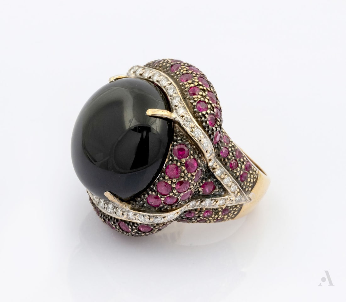 A Designer 18K Two Tone Gold Onyx, Diamond and Gemstone Bombe Ring: A Designer 18K Two Tone Gold Onyx, Diamond and Gemstone Bombe Ring Centered by a large cabochon onyx, mounted on wide, domed band encrusted with red gemstone (likely ruby or tourmaline. )and accented 