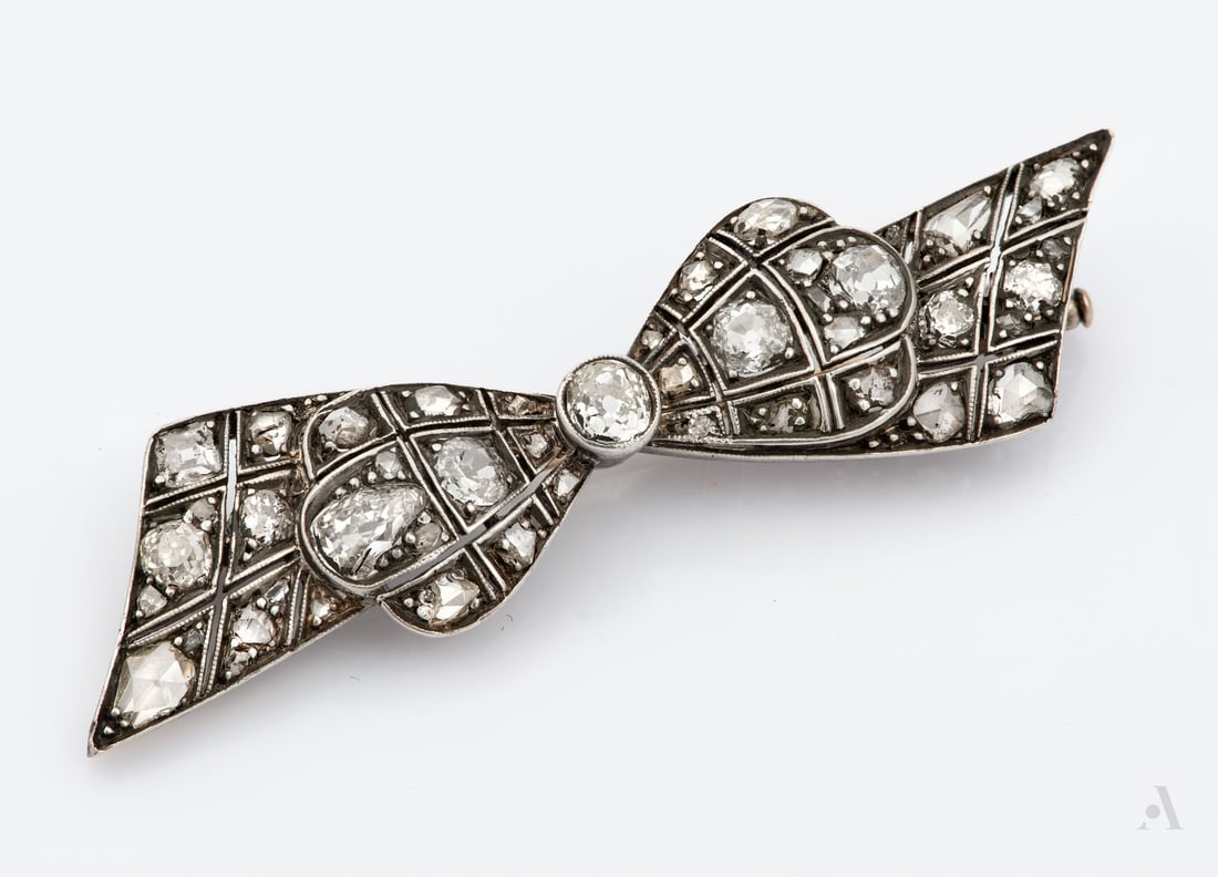 An Art Deco 14K Gold Silvertop and Diamond Brooch: An Art Deco 14K Gold Silvertop and Diamond Brooch Designed as ribbon and set with old-cut diamonds (approx. 1.5 Ct in total). Marked and gold acid tested. Length: 5.5 cm; Total weight: 7 gr Cond