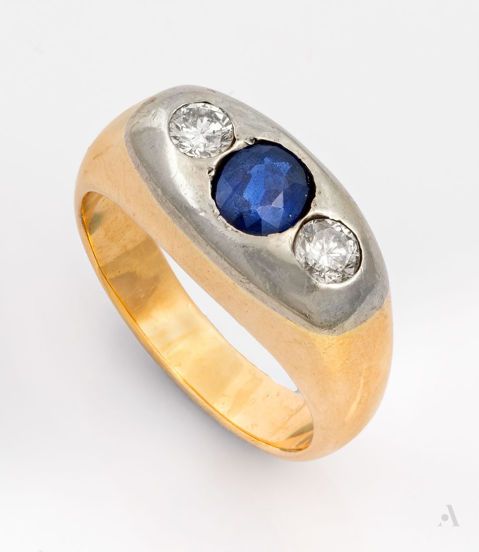 A 18K Two-Tone Gold Diamond and Sapphire Pinky Ring, ca 1900: A 18K Two-Tone Gold Diamond and Sapphire Pinky Ring, ca 1900 Centered by a round cut sapphire and flanked by two round-cut diamonds in an oval white gold head, beneath a wide, rounded yellow gold shan