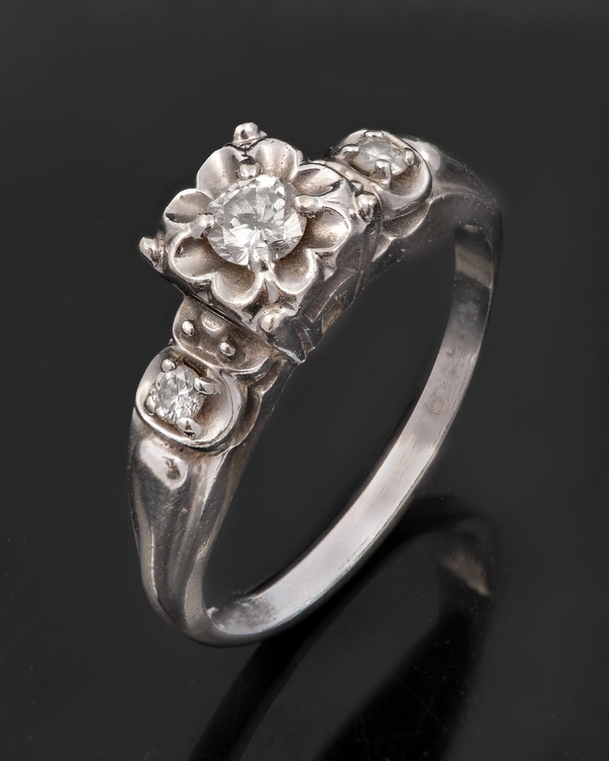 A 14K White Gold and Diamond Ring: A 14K White Gold and Diamond Ring Centered by raised, flower-shaped gallery set with a round brilliant-cut diamond and flanked beneath by two smaller round brilliant-cut diamonds. Gold acid tested. To