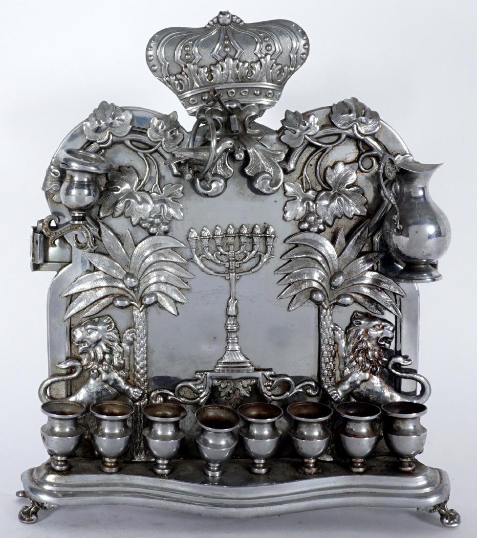 Polish Silver-plate Hanukkah Lamp: POLISH SILVERPLATE HANUKKAH LAMP: Applied crown finial, foliate, lion, and full figure bird decorations. Norblinis Warsaw mark, overall 11" h. x 9 1/2" x 2". Condition: Spotting, looseness to one cand