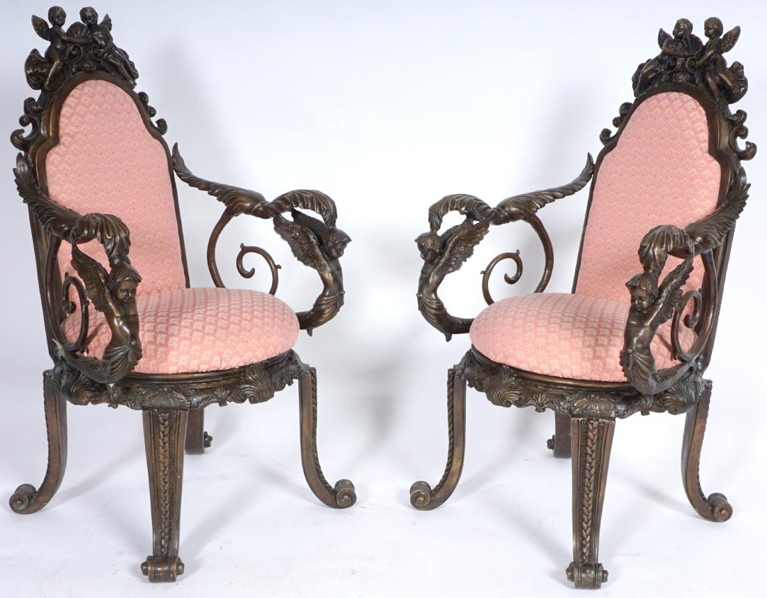 Pair Bronze Figural Cherub Arm Chairs: Contemporary production, Cast bronze frame, figural cherub crest and arm supports, foliate accents. 4 legs ending in scroll feet, patterned upholstery, 43" h. x 24.5" x 23".
