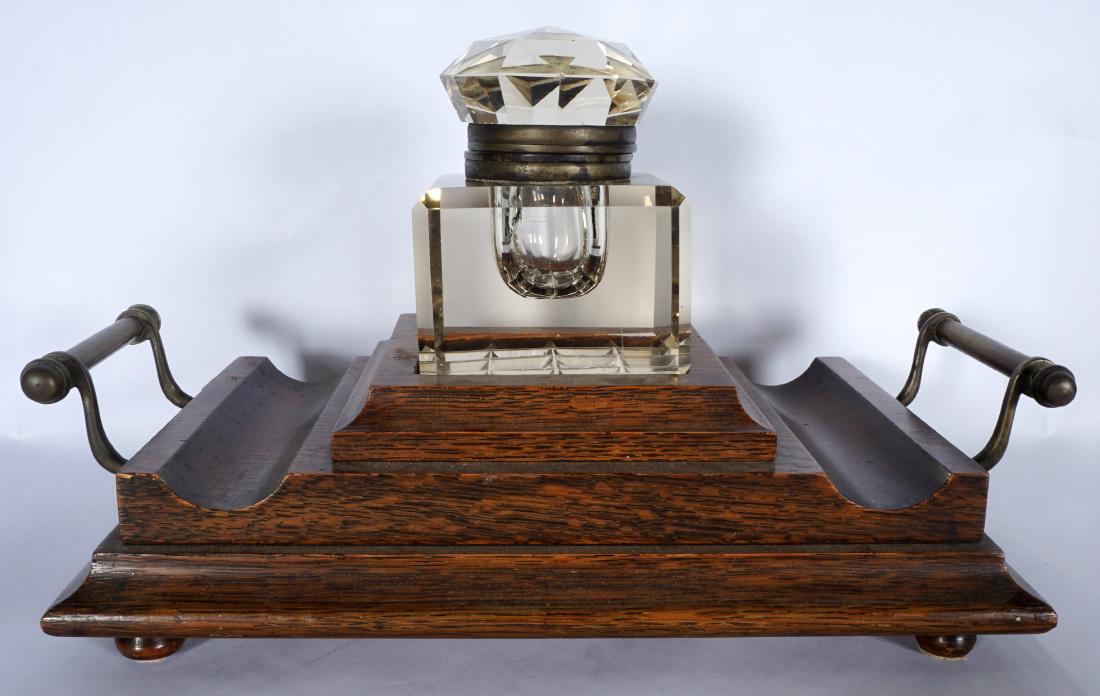 Victorian Oak Inkwell: Stepped oak base with brass handles, crystal reservoir with faceted hinged lid, all on 4 feet. Base 3.5" h. x 13.5" x 8", crystal reservoir 4.5" h. x 3.75" x 3.75". Condition: Internal cracks to reser