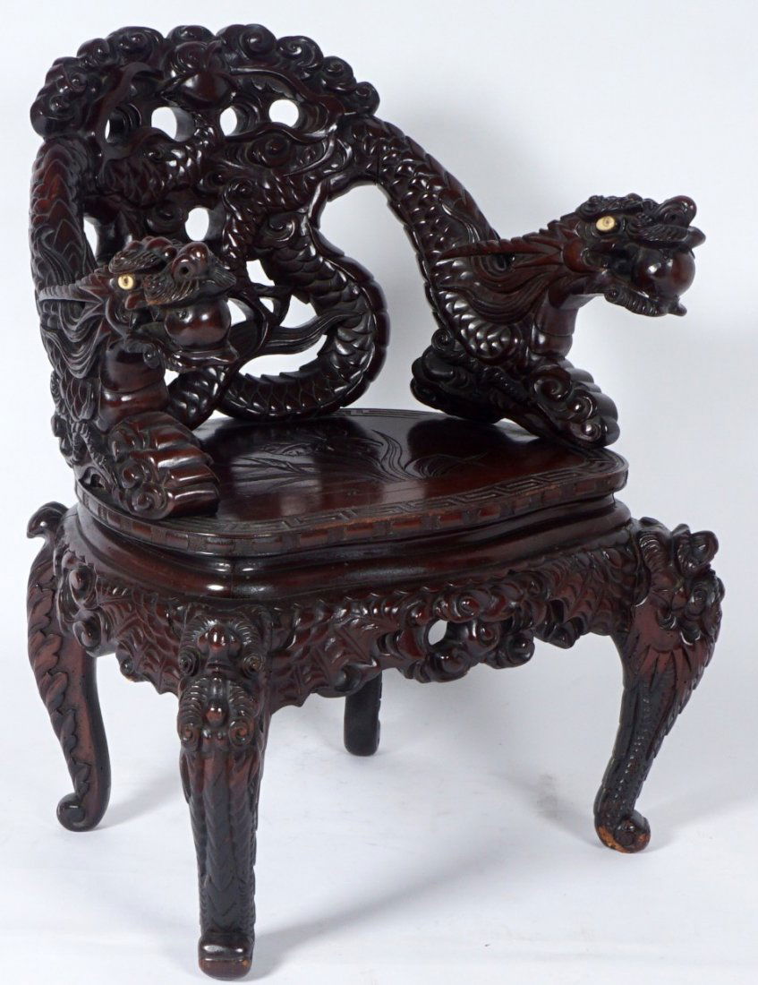 Chinese Carved Dragon Arm Chair: Open work carved back with figural dragon bodies continuing to arms, inset bone eyes. Foliate carved seat, carved and shaped skirt, figural front legs, 34 3/4" h. x 28" x 23". Condition: Missing one e