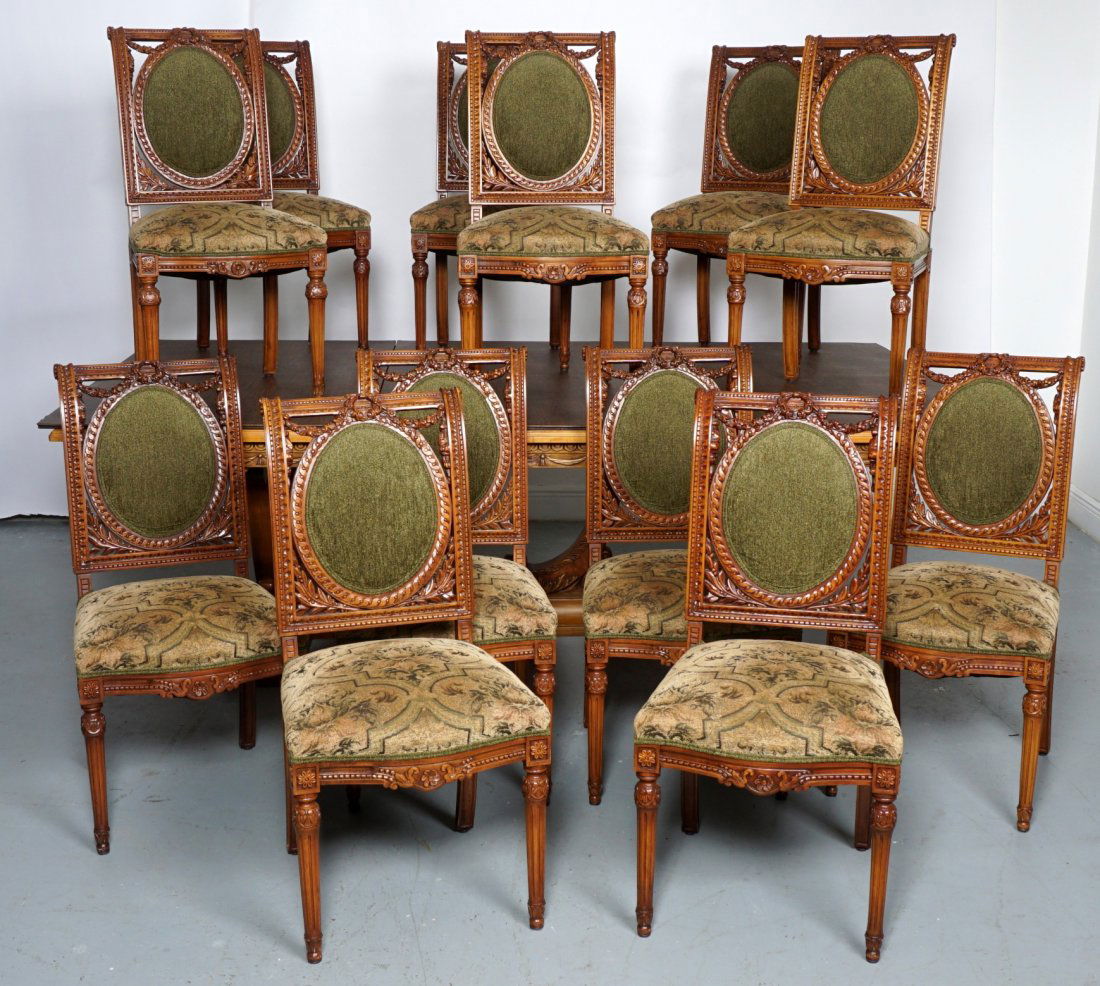 French Mahogany & Burl Dining Table & 12 Chairs: Rectangular top with burl veneer interior, framed with large mahogany band. Carved apron featuring tapestry swag, carved lyre side and center supports, 31" h. x 96" x 58.25". Sold with 12 Louis XVI st