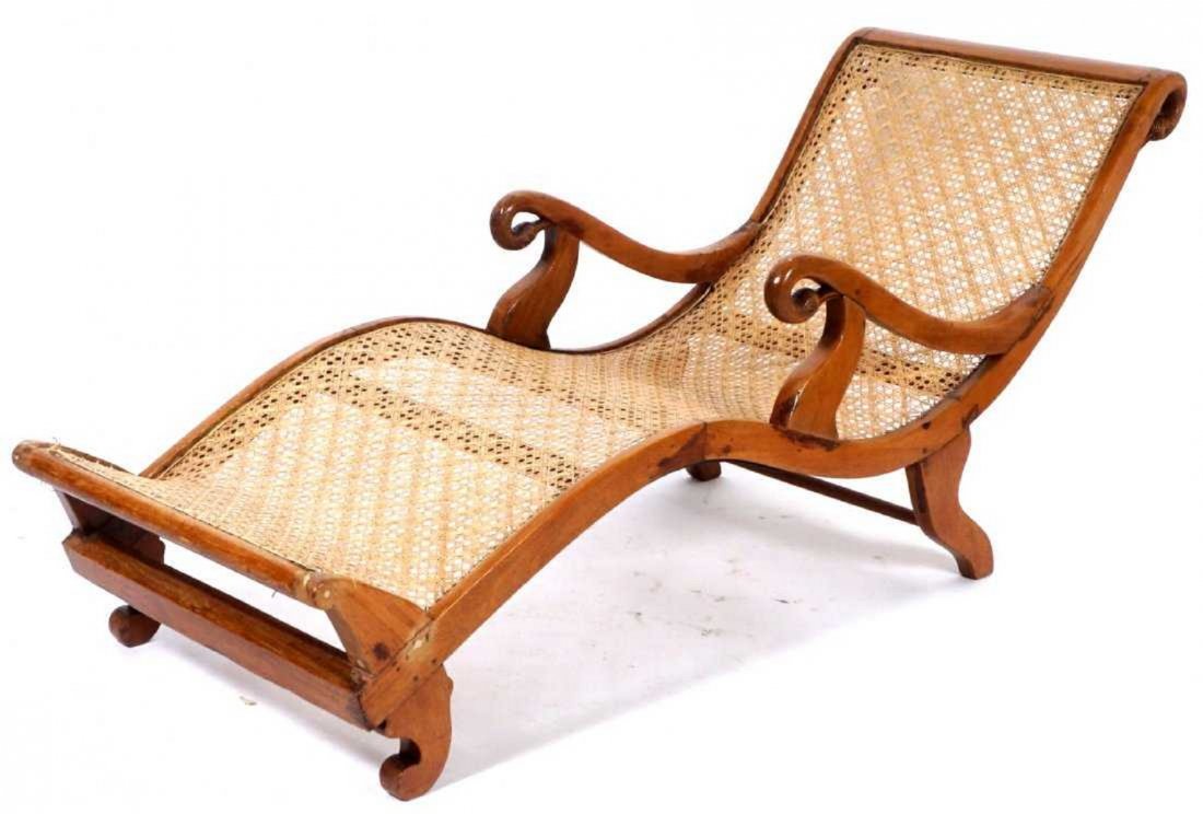 West Indies Caned Plantation Lounge Chair: Serpentine shaped chaise lounge frame with carved swan heads at top and hand holds. Shaped feet, overall measures approx. 33.25" x 27.25" x 72". Condition: Small issue with caning near end.
