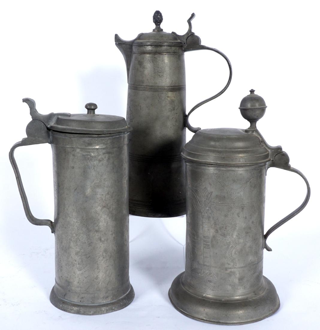 Three 18th Century Pewter Flagon & Steins: An assembled collection of 3 flagon and steins, all most likely German, to include 1) Hinged lid flagon with pineapple finial, engraved floral medallion, owners name Georg Hufnagel and dated 1774. 11.
