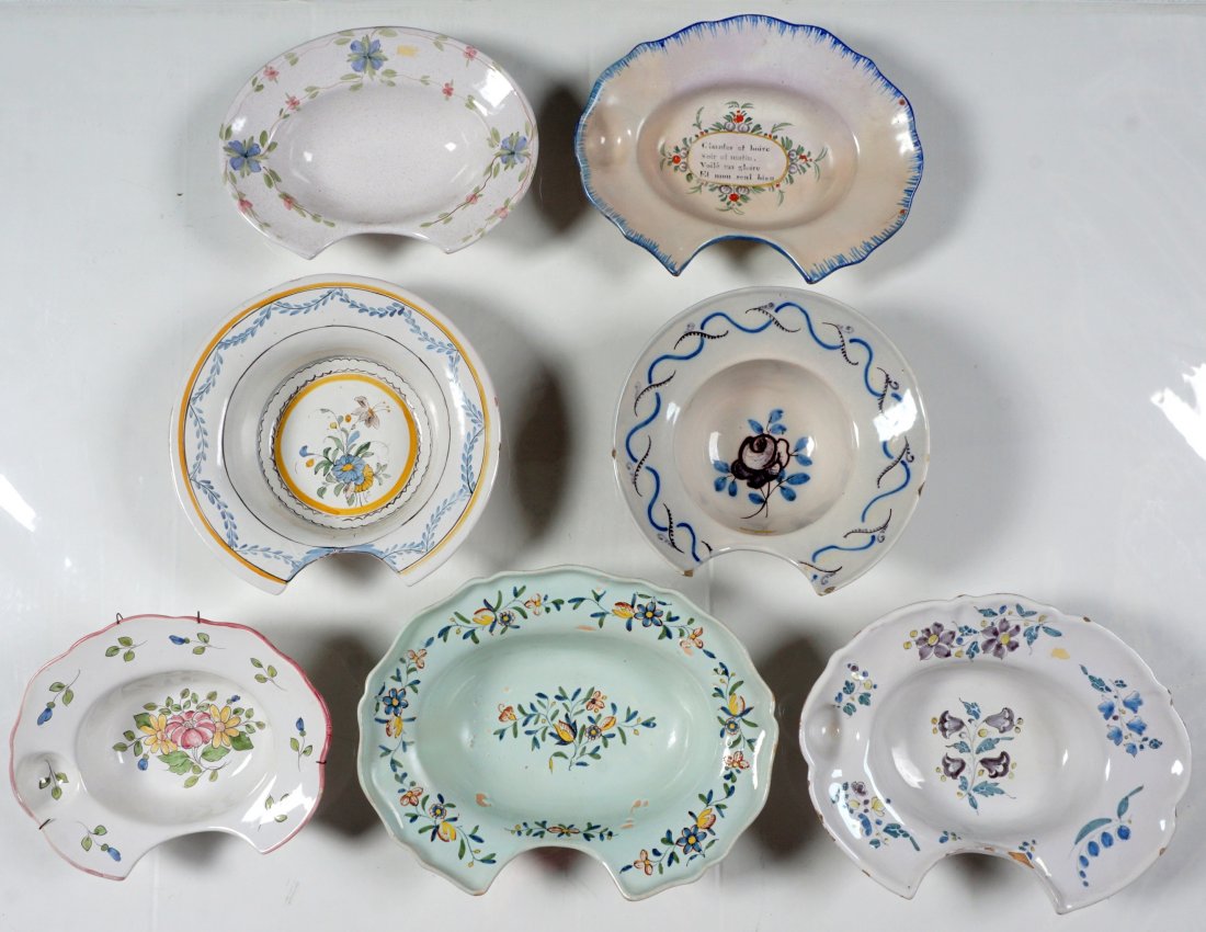 7 French Faience Shaving Bowls: An assembled collection of 7 total, floral motifs, largest measures 3.25" x 13" x 10". Condition: All but one with at least one chip, several with cracks and/or repairs.