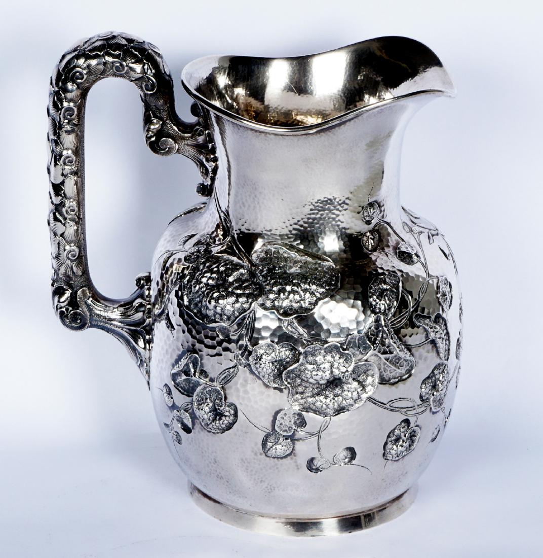 Bigelow Kennard Sterling Silver Japanesque Pitcher: Aesthetic movement sterling silver pitcher, chased repousse and hand hammered in the Japanesque style with water lilies, floral design applied handle, footed base. Marked Bigelow, Kennard & Co., Sterl