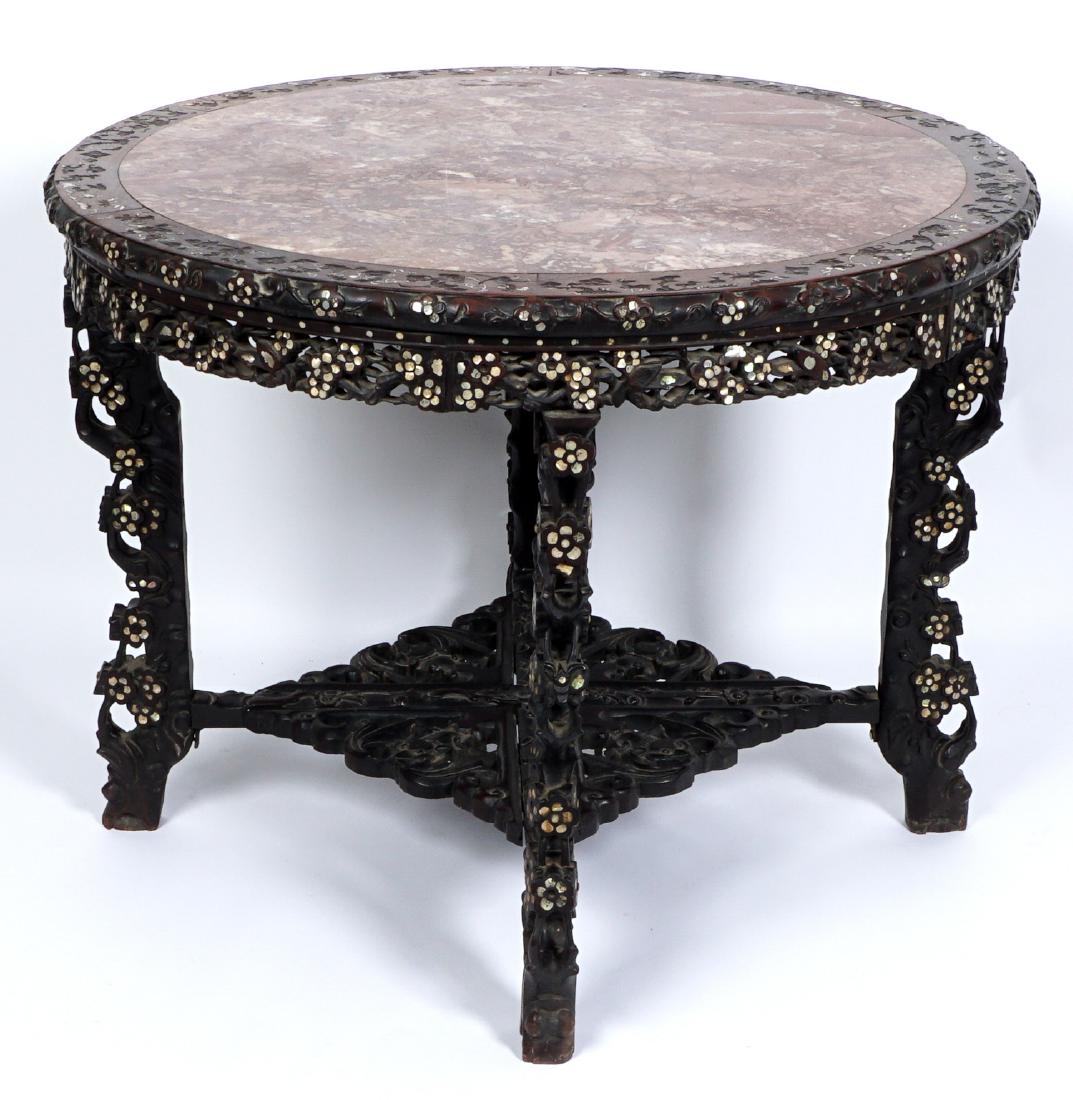 19th C. Chinese Carved MOP Inlaid Center Table: Round inset variegated marble top bordered with inlaid mother of pearl designs. Pierced carved skirt and legs with inlaid floral accents, lower pierced carved stretcher shelf with stylized figural bat