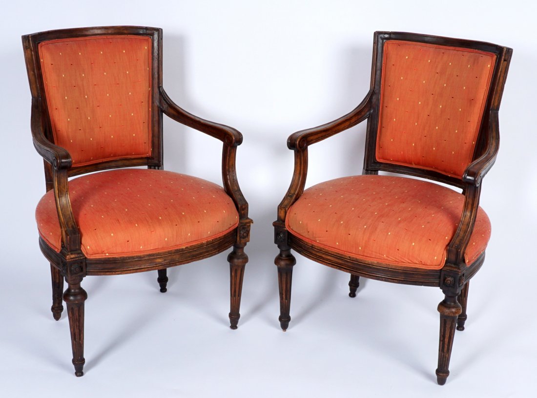 Pair 18th Century Italian Arm Chairs: Italian Walnut frames, curved backs, scroll hand holds with shaped supports. Skirt with carved floral medallions at joints, fluted legs, overall 36" h. x 24" x 23". Wear consistent with age and use.