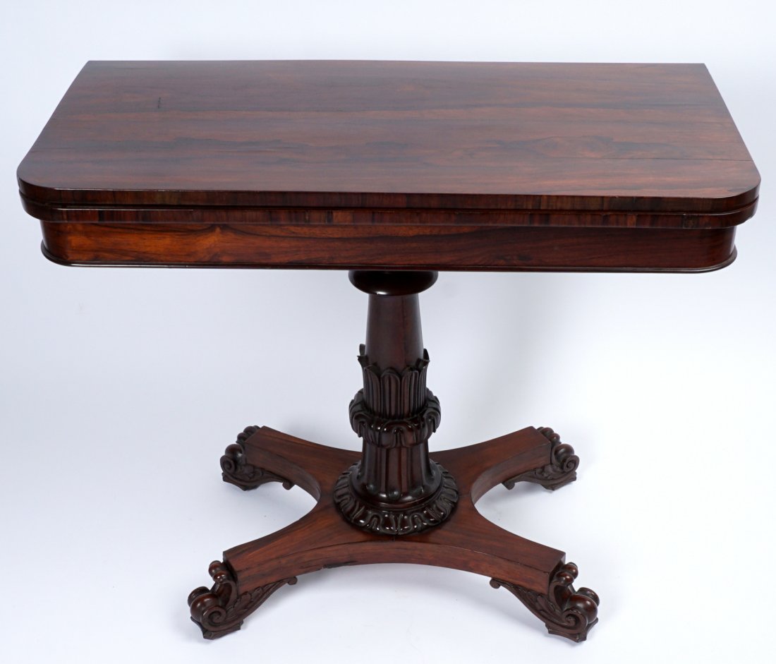 Regency Rosewood Game Table: Top flips and rotates to open to a red felt playing surface, carved column support, splayed base ending in scroll carved feet, 30" h. x 36" x 18". Condition: Wear to felt, other wear consistent with a