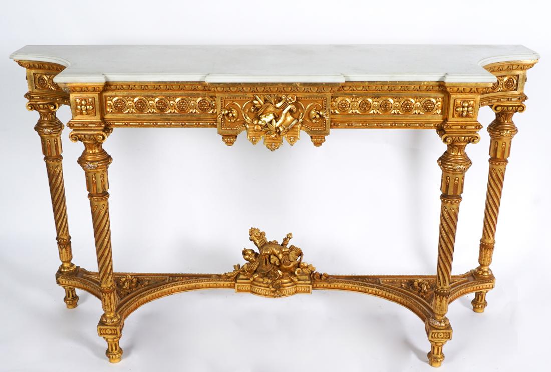 Louis XVI Style Carved Marble Top Console Table: Shaped white marble top conforming to carved gilt wood base. Skirt with theatric theme center decoration and medallions, carved and turned supports. Stretcher with center musical instruments finial, f