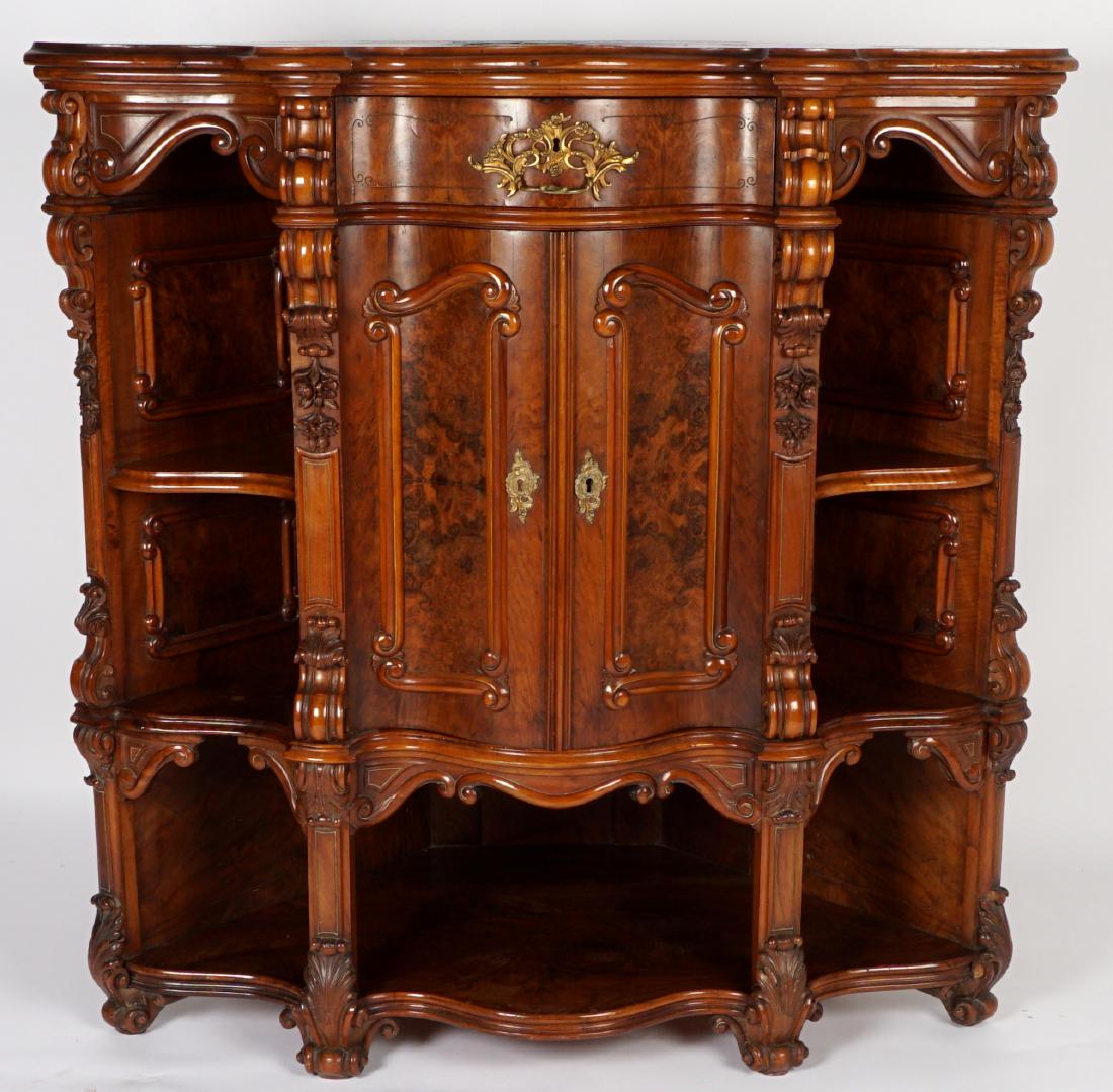 Continental Carved Serpentine Corner Cabinet: 19th Century burl veneer case etagere corner cabinet, serpentine top and front, center single drawer over 2 doors over open lower shelf, open shelves either side. Carved stiles, valences, and front fe