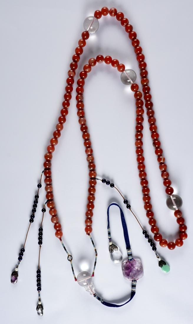 Chinese Carnelian Red Agate Prayer Beads: Approx. 15mm dia carnelian or red agate beads with larger crystal beads, drops with purple quartz, jade, and crystal medallions. Approx. 72" long excluding drops. Condition: Chip to largest purple qua