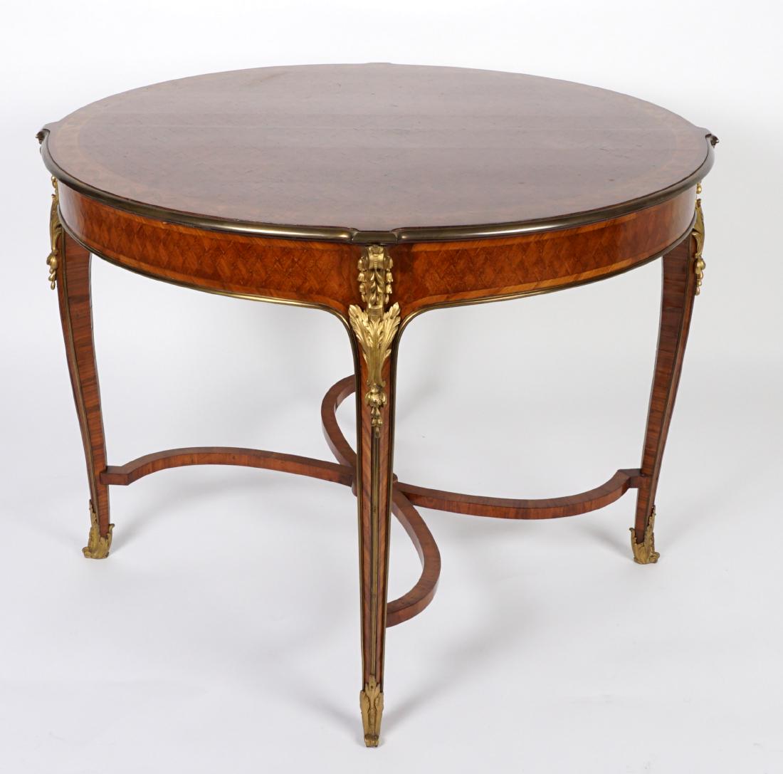 French Parquetry and Ormolu Mounted Center Table: Diamond pattern parquetry inlaid round top and skirt, top bordered with wave design band, brass trim. Ormolu mounts at leg joints and feet, curved stretchers with center medallions. Overall 30.5" h. x