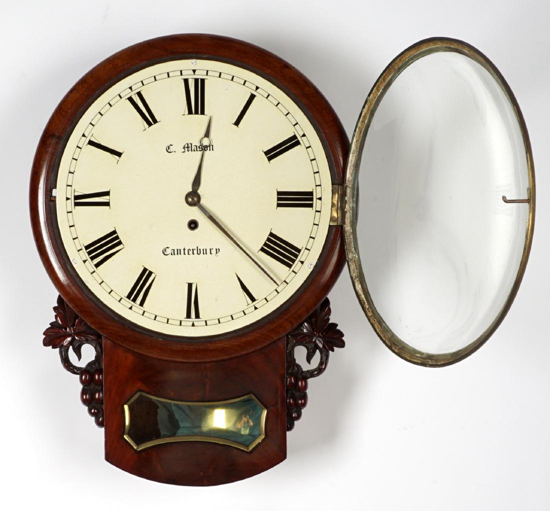 C. Mason English Fusee Wall Clock: Mahogany case with carved fruit and leaves accents. Convex crystal, painted metal dial with Roman numerals, signed C. Mason, Canterbury. Single fusee brass time only movement, overall 20.5" h. x 15" x