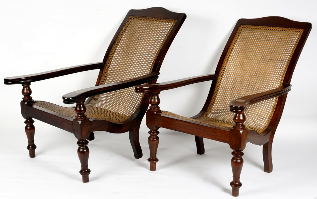 Pair West Indies Caned Plantation Chairs: Circa 1900, tropical hardwood frames, arms with rotating extensions, caned seat and back, 39" h. x 44" x 30.5". Condition: Wear consistent with age and use.