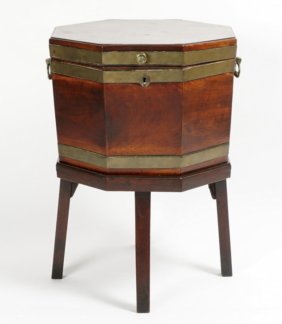 Regency Mahogany Cellarette on Stand: Octagonal mahogany body, brass bands and handles, wood divided interior, on fitted stand with splayed legs. Overall 26.25" h. x 19" Condition: Age splits, veneer bubble, stains and chips.