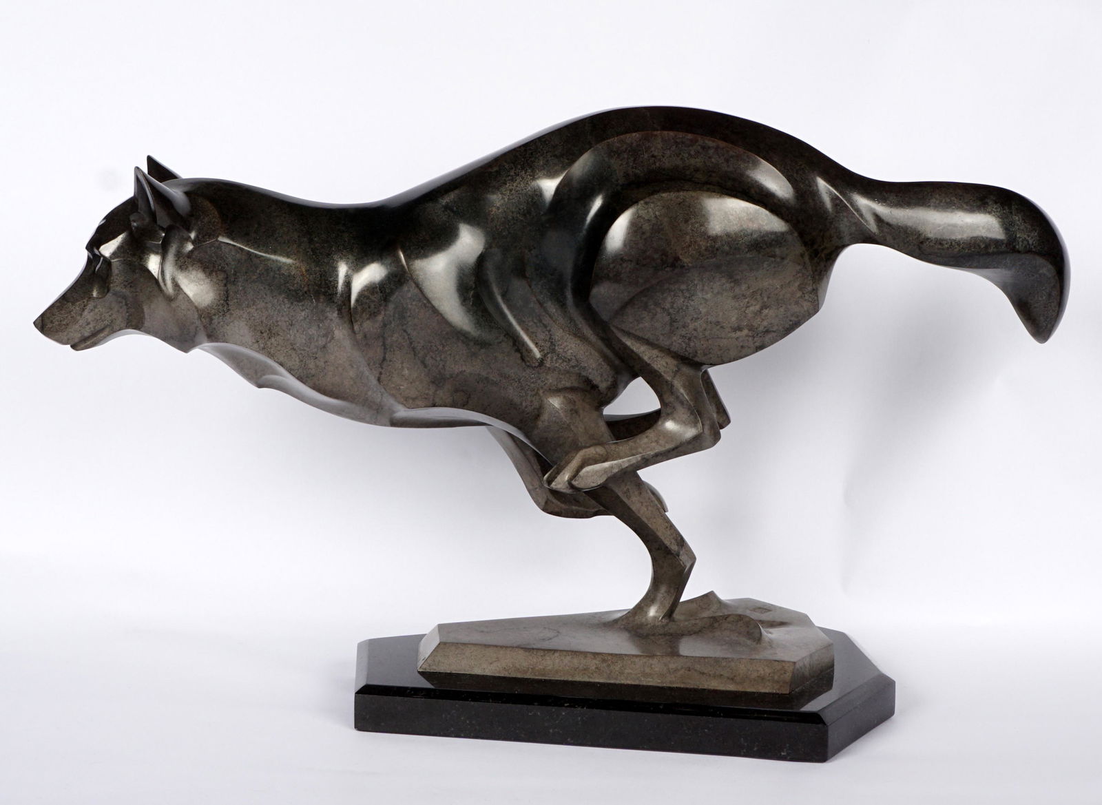 Janet Rosetta Breaking Trail Wolf Bronze: ROSETTA, Janet, (American, 1945-): "Breaking Trail", patinated bronze sculpture of a running wolf, impressed mark and numbered 3/24, affixed to stone plinth, 11.5" h. x 19.25" x 7.75".