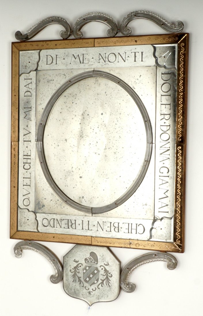 Venetian Style Mirror: 20th Century, crest with center heraldic shield , oval center framed in raised glass trim, outer frame with motivational writing, lower scroll crest. Overall 48.5" x 31". Condition: Missing trim piece