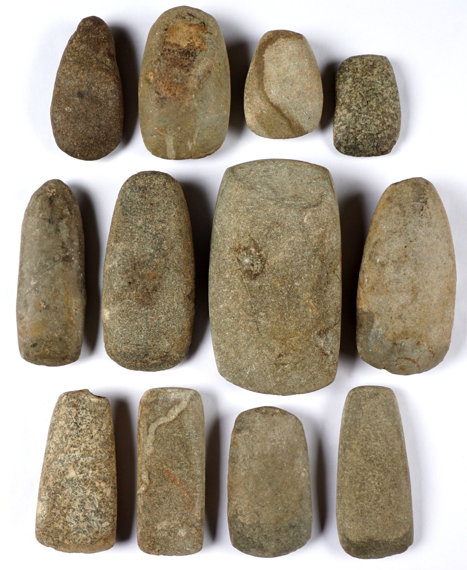 Twelve Archaic Era Native American Celts: Twelve pieces total, three marked with Kentucky locations, another with Ohio location, most with collection numbers written on them largest measure 5.75" h. x 3.25". From a prominent Kentucky collecti