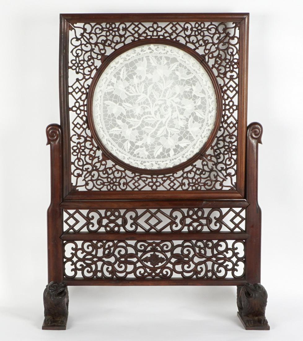 Chinese Figural Temple Lions Table Screen: Carved wood base, intricately carved with two panel, feet with recumbent temple lions or mythological creatures. Removable center panel with matching carvings, glass medallion with foliate embroidery.
