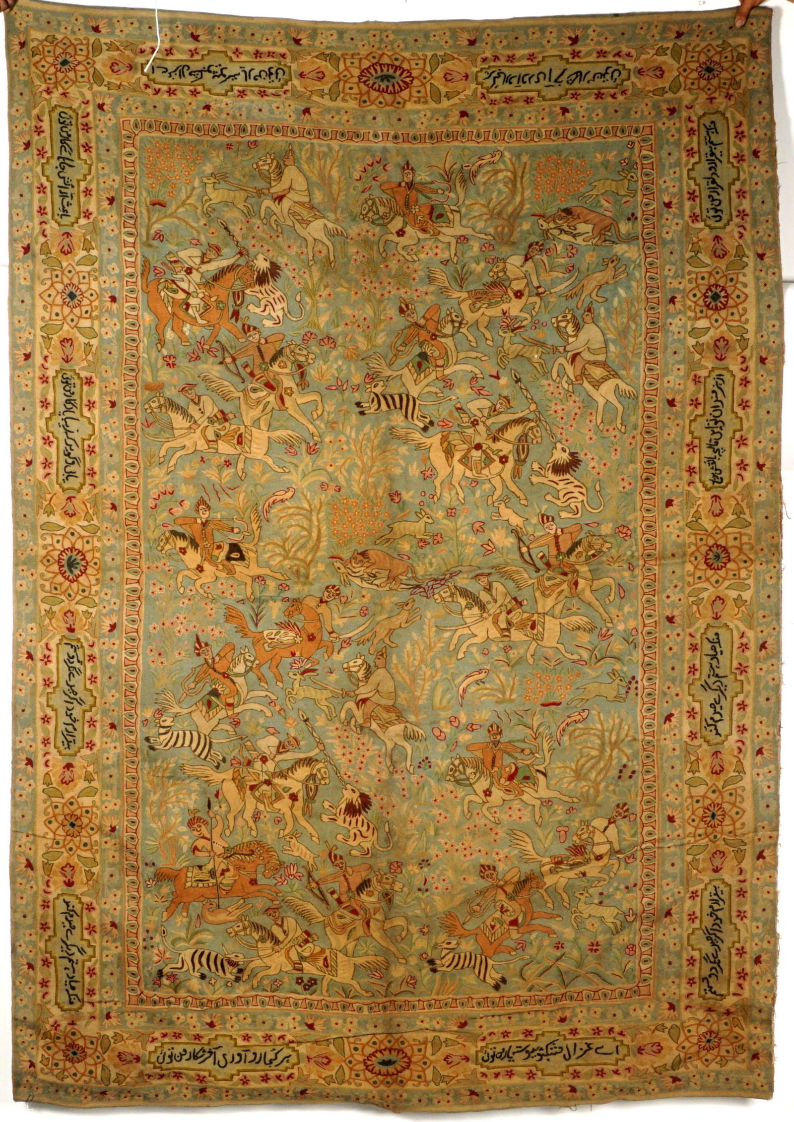 Persian Hunt Scene Tapestry: 20th century, center portraying a hunt scene with assorted exotic animals, multiple figures on horseback, lions engaging in the hut as well. Banded border, signed in lozenges, floral decoration, 5' 10