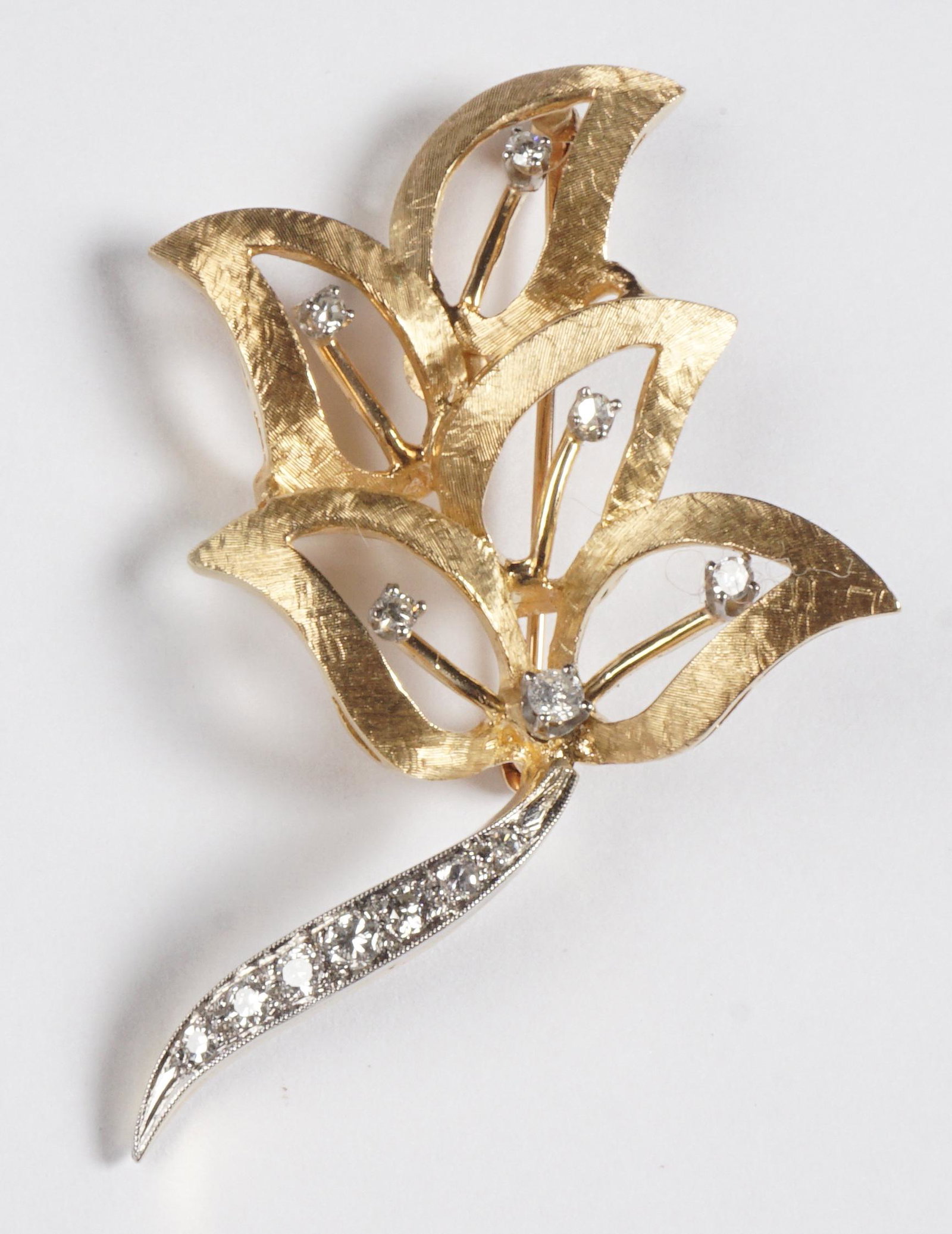 14k Yellow Gold and Diamond Leaf Pin: Foliate leaf form 14k gold pin with 13 channel and prong set diamonds, signed on back, 2" h., approx. 8 grams inclusive.