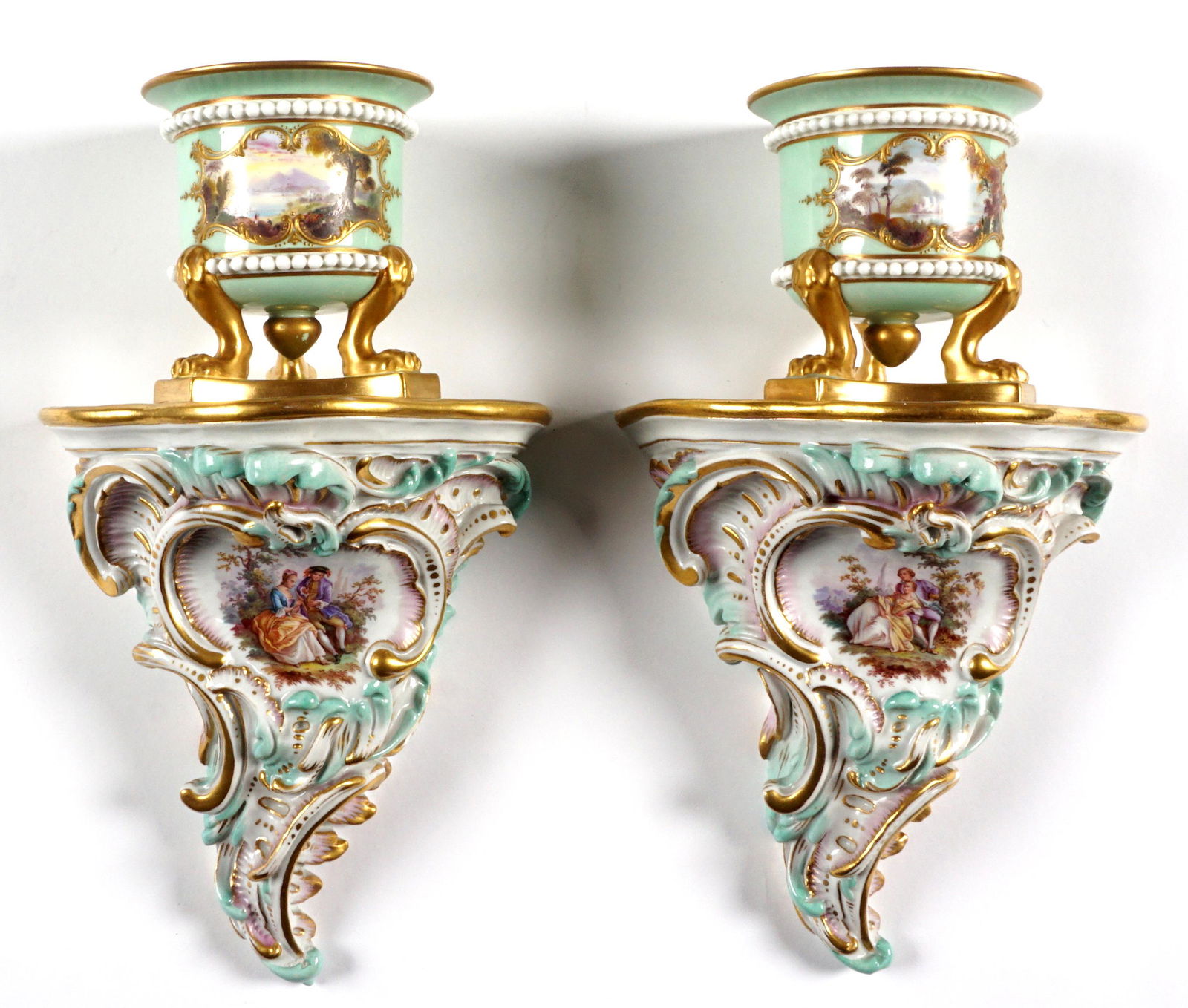 Pair Meissen Porcelain Wall Sconces: Pair Meissen marked sconces, light green ground, urn on paw feet over rococo style self, hand painted vignettes. Blue crossed sword marks, incised 1423, overall 10.25" x 6.25" x 4..75". Condition: One