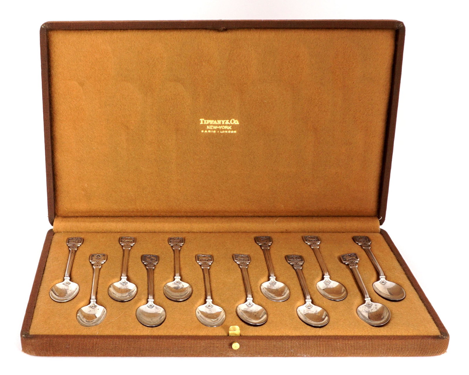 Twelve Tiffany Sterling Zodiac Demitasse Spoons: Set of twelve demitasse spoons in the Zodiac pattern by Tiffany & Co., in original presentation box. Each spoon 4" long, case measures 11" x 6.5". Condition: Loss to cover of case.
